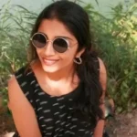 girl sitting and smiling, wearing sunglasses
