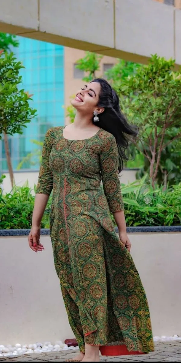 actress standing by wearing an anarkali made by a fashion designer in Kochi.