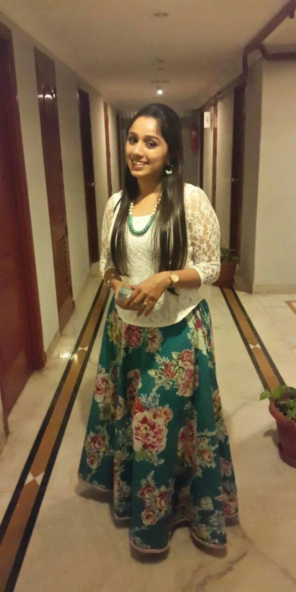 actress standing in a corridor wearing a skirt and top made by a fashion designer in Kochi.