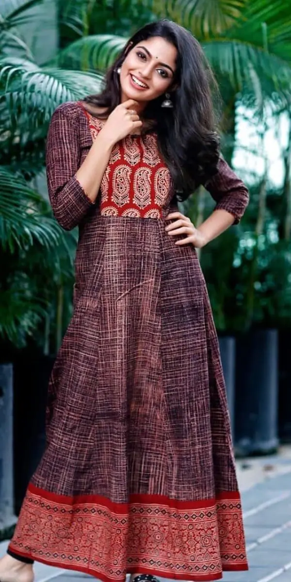 actress smiling and standing wearing an anarkali made by a fashion designer in Kochi.