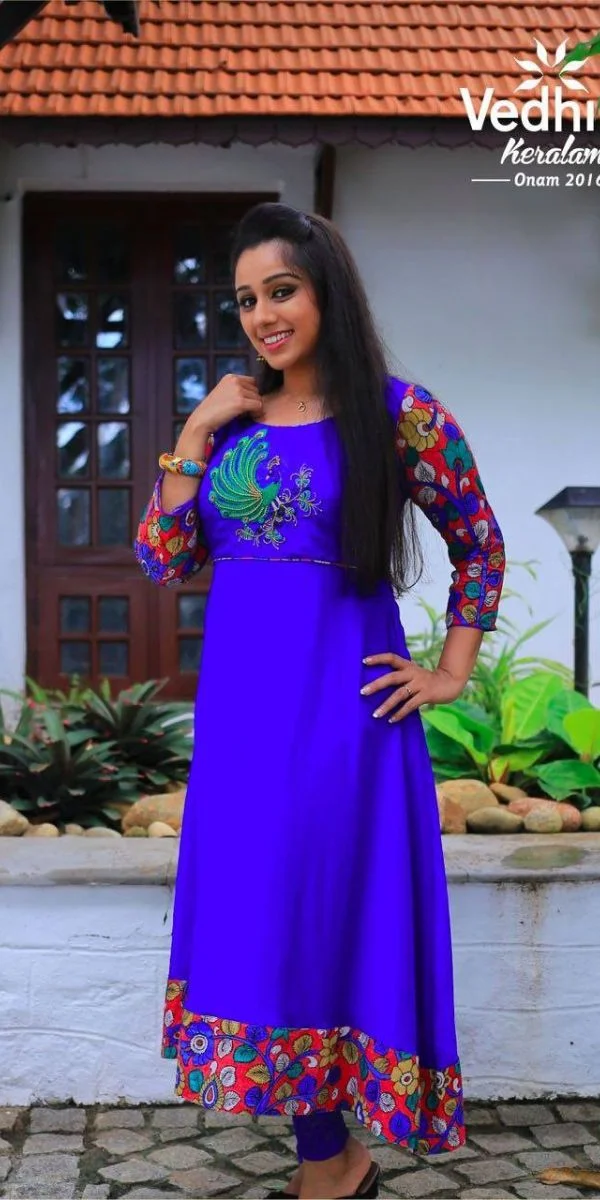 actress smiling and standing wearing an anarkali made by a fashion designer in Kochi.
