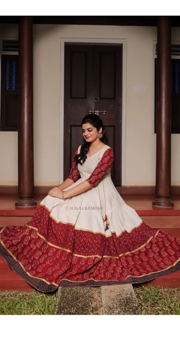 actress smiling and sitting down wearing an anarkali made by a fashion designer in Kochi.