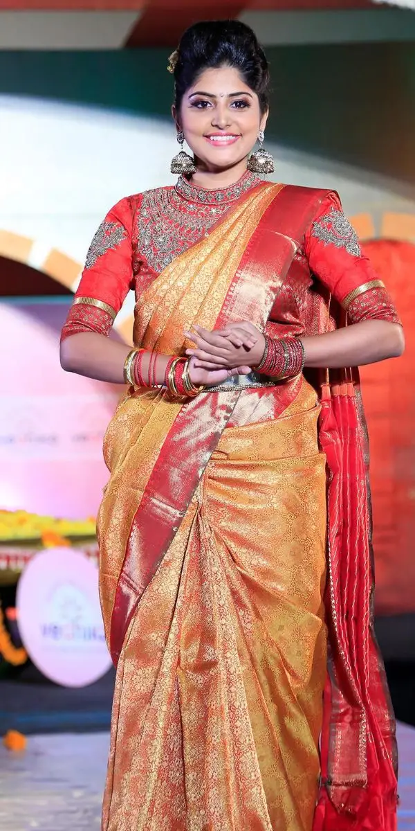 actress smiling and standing wearing an saree made by a fashion designer in Kochi.