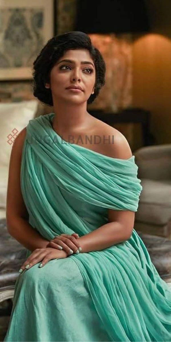 actress posing and sitting in a chair, wearing skirt and top made by the fashion designer in Kochi.