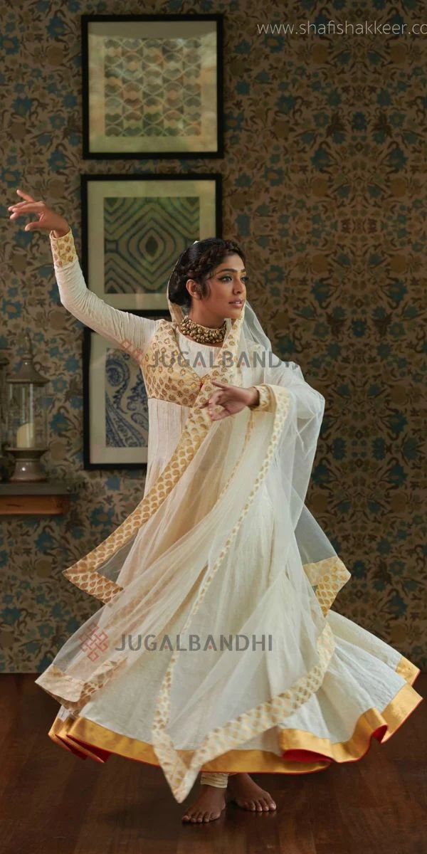 actress dancing in a room ,wearing anarkali made by a fashion designer in Kochi.